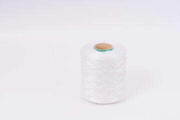 A spool of white braided fiberglass thread with a green core, isolated on a white background. Industrial material concept with copy space.