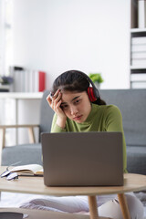 Young Woman Experiencing Stress While Working Online at Home with Laptop and Headphones