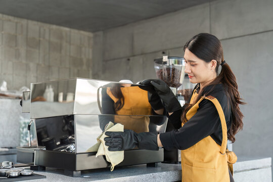 Female Employee Cleaning Coffee Shop Espresso Machine with Care and Precision in Modern Cafe Setting
