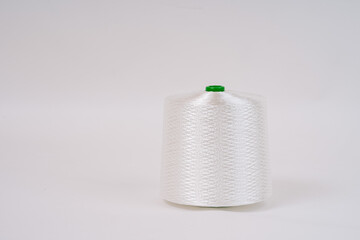A spool of white fiberglass thread with a green top, displayed against a plain white background, showcasing the texture and weave of the material...