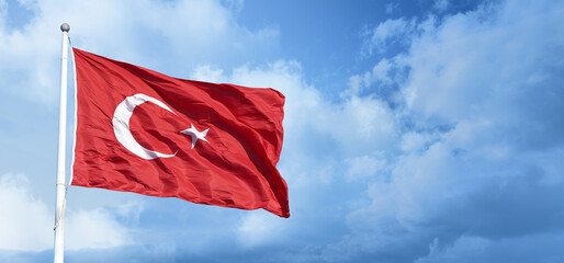 Turkish flag waving in the blue, cloudy sky.