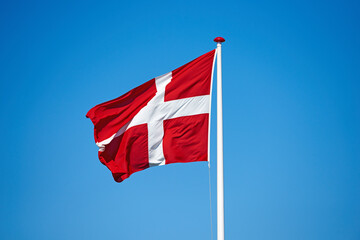 Flag, blue sky and denmark with symbol of scandinavian country or danish state with red and white cross. Wind, pole and colorful representation of Dannebrog, history or nation in Copenhagen or Europe