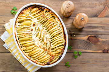 Potato zucchini bake in baking dish on wooden background. top view, copy space.