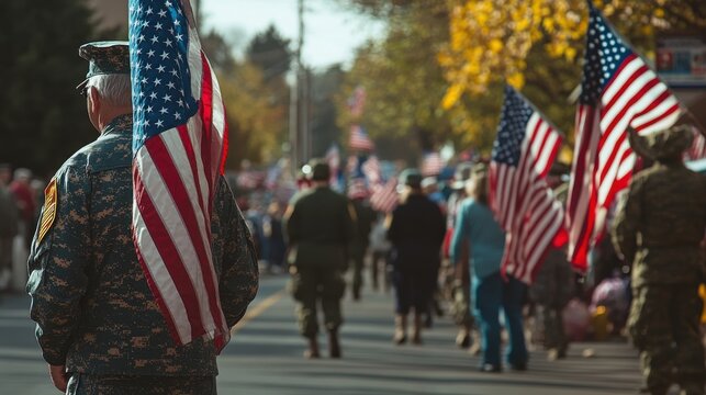 A group of people participating in a Veterans Day parade, carrying American flags, some dressed in military uniforms, and others in civilian clothes, showing respect and gratitude to those who served