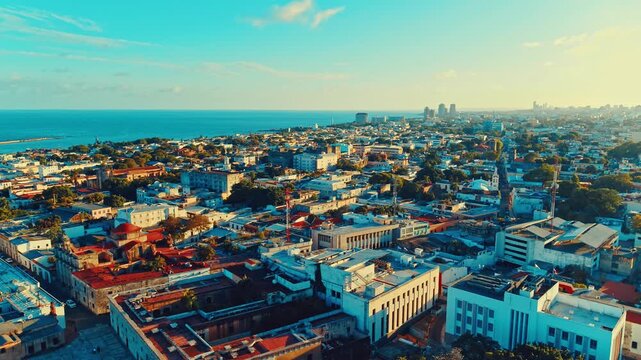 Aerial view of the picturesque seaside city of Santo Domingo during sunset. Sea horizon under the evening sky. Orbital drone shot. Caribbean coastline landscape. Capital of the Dominican Republic.