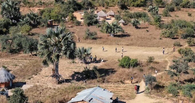 Soaring over beautiful Zambia village with kids playing soccer