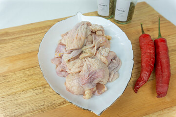 Fresh Raw Chicken Skin on white plate and chili, lemon as a decor on cutting board