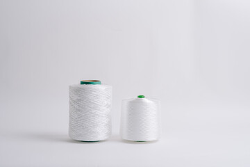 Two spools of white fiberglass thread with green cores, placed side by side on a white background, showcasing different sizes.