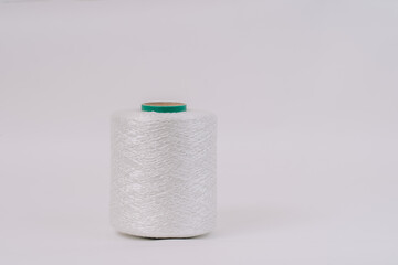 A spool of white braided fiberglass thread with a green core, isolated on a white background. Industrial material concept with copy space.