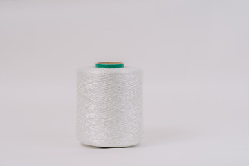 A spool of white braided fiberglass thread with a green core, isolated on a white background. Industrial material concept with copy space.