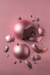 A broken New Year's ball. Christmas tree toy on a solid pink background. small pieces with sequins