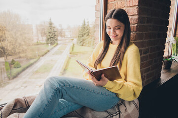 Obraz premium Photo portrait of attractive teen woman read book sit windowsill dressed yellow outfit cozy day light home interior living room
