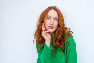 A woman with red hair is wearing a green sweater and is looking at the camera