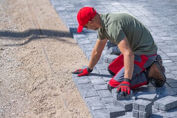 Construction worker laying paving stones on a pathway at a construction site