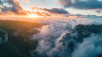 Naklejka premium Golden sunlight paints vibrant sky as clouds embrace majestic mountains