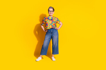 Fototapeta premium Photo of cheerful glad senior woman wear stylish print clothes empty space isolated on vivid yellow color background
