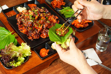 식탁 위에 놓여 있는 불족발을 쌈을 싸서 맛있게 먹는 모습