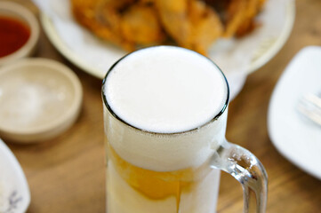 식탁 위에 있는 생맥주 잔의 거품을 확대한 모습