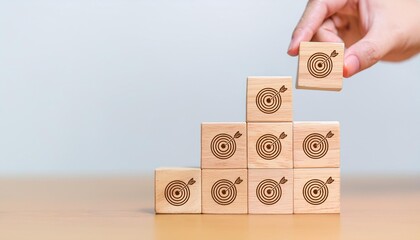 Hand holding wooden block with target aiming dart board and arrow up on table background. Business achievement objective goal and project progress growth value processing marketing financial concept