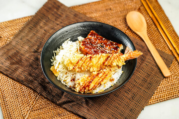 Grilled Eel with Deep Fried Shrimp Donburi with rice, chopsticks and spoon served in bowl isolated on napkin side view of Japanese food