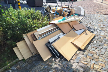 A heap of assorted discarded household items and furniture piled up on a cobblestone street,...