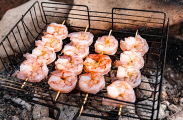 Grilling shrimp over an open fire in the woods.