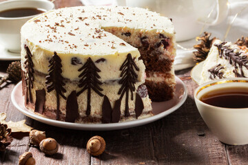 Tea party with Black Forest cake. Cherry cake decorated with chocolate fir trees on a light background.
