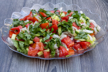 Seasonal salad. Mediterranean salad with tomatoes, peppers, onions, arugula and olive oil.