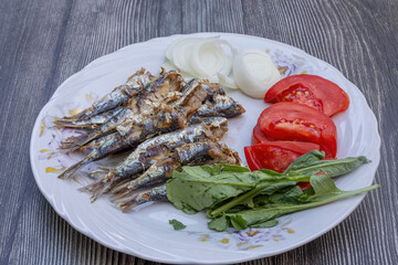 Grilled sardine fish with tomatoes, onions and arugula on a white plate. Healthy meal.