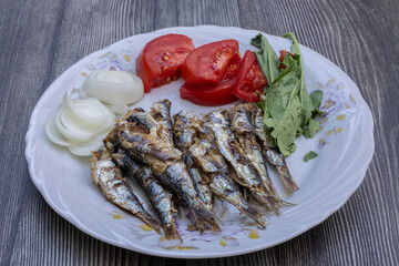 Grilled sardine fish with tomatoes, onions and arugula on a white plate. Healthy meal.