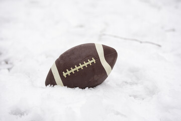 a football covered with snow and laying in the snow