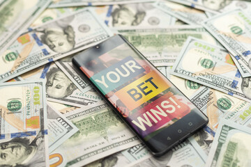 Smartphone with gambling mobile application with money close-up. Sport and betting concept