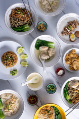 An overhead shot of a variety of Asian dishes including noodles, rice, soup, and wontons, arranged on a marble table, ideal for showcasing a diverse culinary spread perfect for food photography