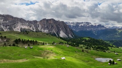 Aerial view of the rocky peaks of the Seceda Mountain touching the clouds in the Dolomites, Italy