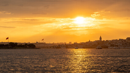 Naklejka premium Golden rays of the sun illuminate the Bosphorus as the skyline of Istanbul subtl