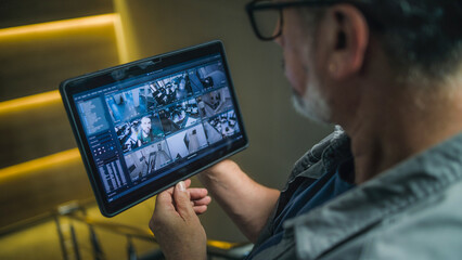 Male installer watches CCTV cameras in stylish office using tablet computer. Real time view of...