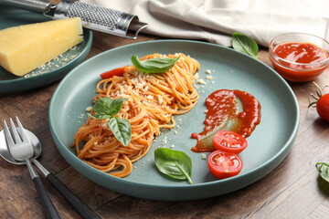 Delicious pasta with tomato sauce, basil and cheese served on wooden table, closeup