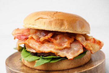Delicious burger with bacon and greens on white background, closeup