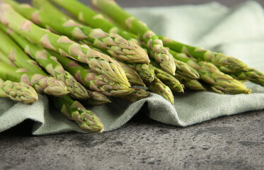 Fresh green asparagus stems on grey textured table, closeup