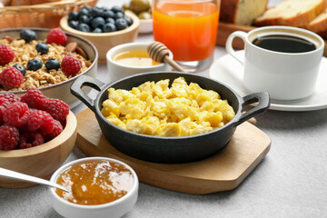 Tasty breakfast. Scrambled eggs, coffee, jam and other food on grey textured table, closeup