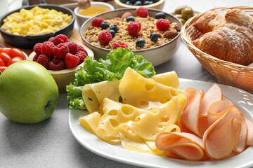 Tasty breakfast. Slices of ham, cheese, lettuce, apple and other food on grey textured table, closeup