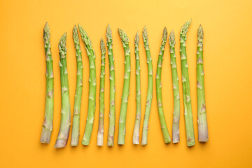 Fresh green asparagus stems on orange table, top view