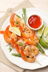 Skewers with delicious grilled shrimps served on wooden table, top view