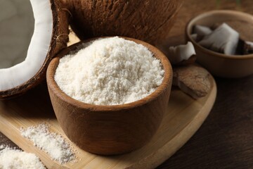 Coconut flour in bowl and fresh fruits on wooden table, closeup