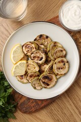 Tasty grilled courgette slices served on wooden table, flat lay