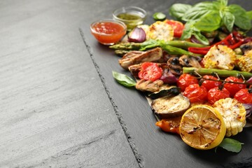 Delicious grilled vegetables served on grey textured table, closeup. Space for text