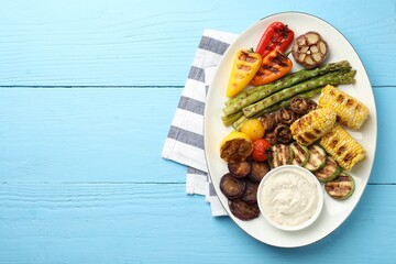 Delicious grilled vegetables with sauce on light blue wooden table, top view. Space for text