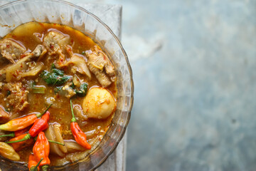 Seblak is a typical Indonesian dish with a savory and spicy taste. Made from wet crackers cooked with vegetables, sausage, eggs. a bowl of seblak on a wooden table.