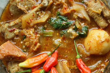 Seblak is a typical Indonesian dish with a savory and spicy taste. Made from wet crackers cooked with vegetables, sausage, eggs. a bowl of seblak on a wooden table.