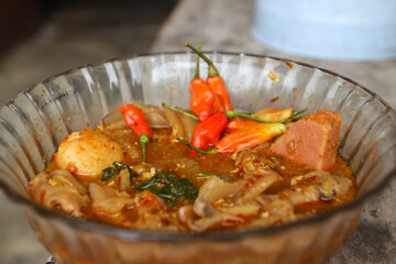 Seblak is a typical Indonesian dish with a savory and spicy taste. Made from wet crackers cooked with vegetables, sausage, eggs. a bowl of seblak on a wooden table.